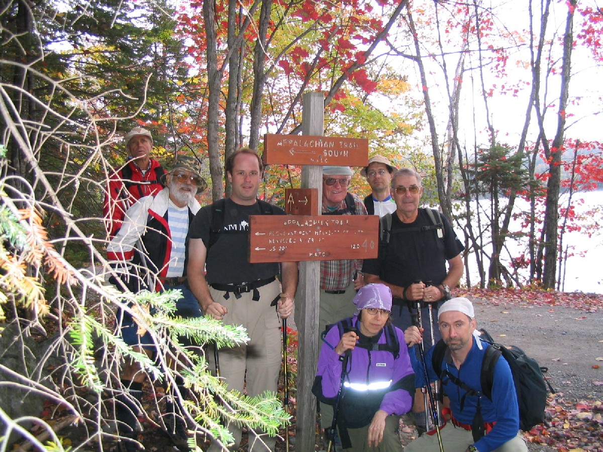 25.0 MM. This is the Moxie Pond Trailhead as the AT heads west into the woods to start its climb up Pleasant Pond Mountain. Moxie Pond is in the background. Ludwig, Dean, Josh, George P., Chris, George S. Veronica and Dave pose in this photo at the start of this day's hike. Courtesy askus3@optonline.net